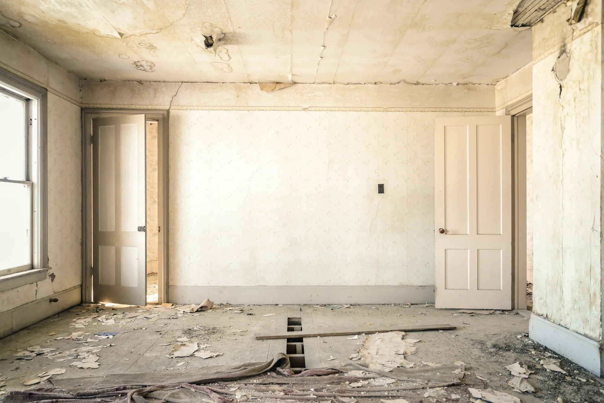 Doorway sealed with plastic dust barrier and floor runner leading into a room under renovation
