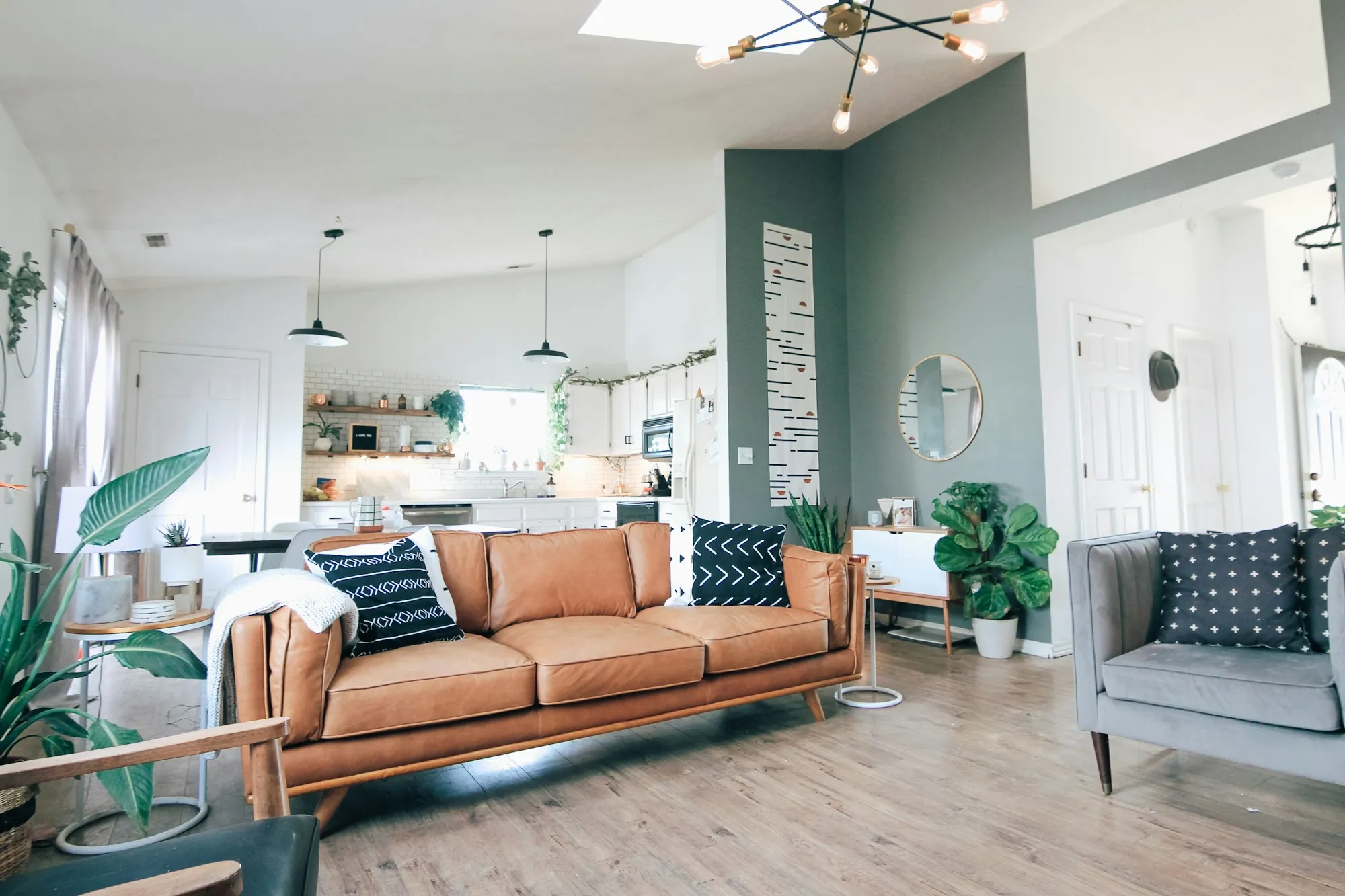 Open living room and kitchen with a green accent wall and light wood floors