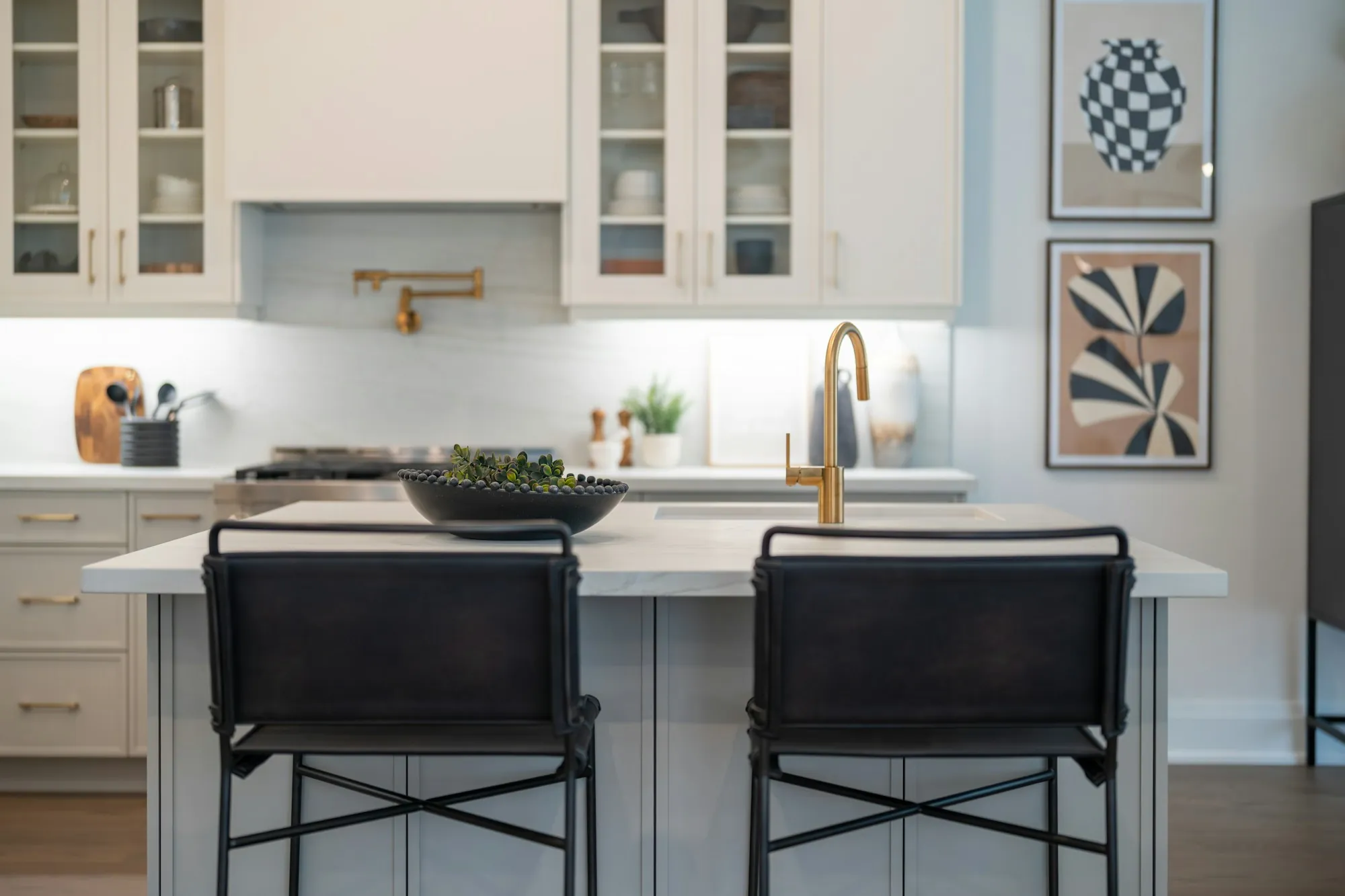 Remodeled kitchen island with white counters, glass-front cabinets and black bar stools
