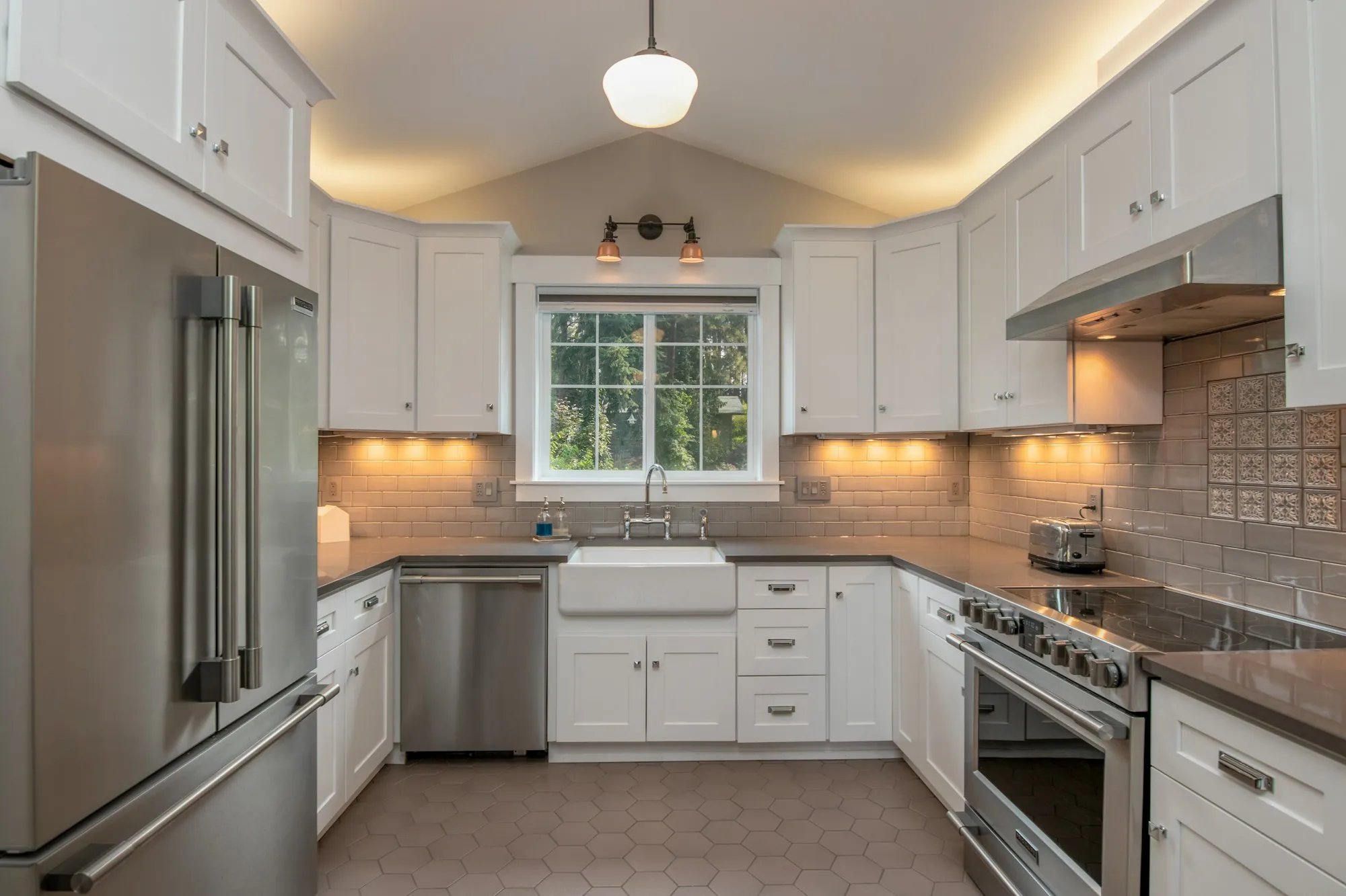 White shaker kitchen with under-cabinet lighting, subway tile backsplash and farmhouse sink