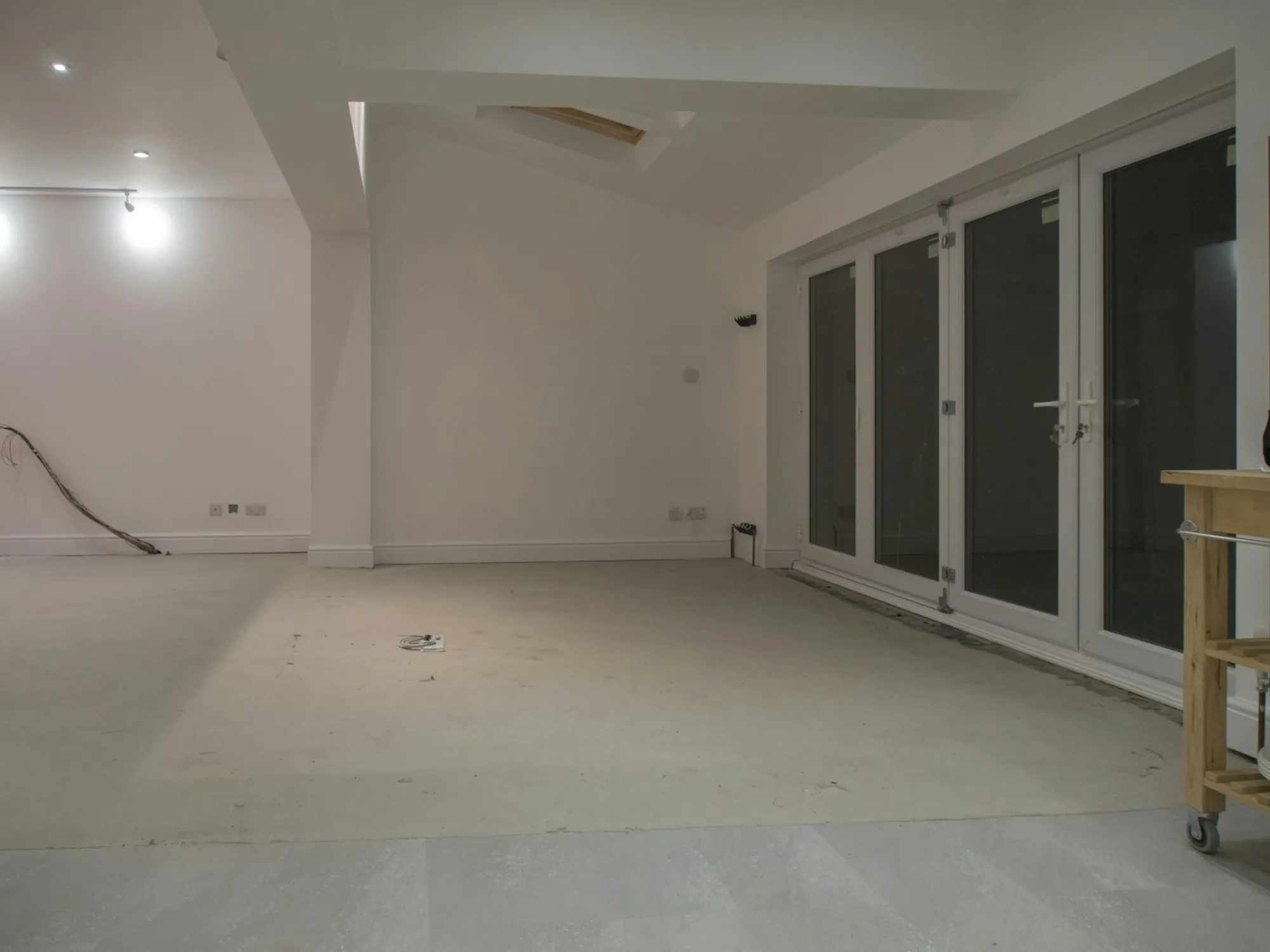 Gutted room with bare subfloor and new patio doors ready for finishing