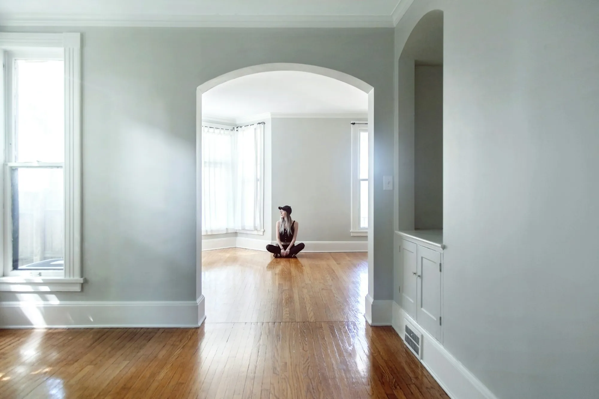 Freshly painted gray walls and arched doorway over refinished hardwood floors